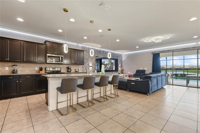 8801 Macapa Dr, Kissimmee, FL 34747 - kitchen with stainless steel microwave, electric range, light tile patterned floors, open floor plan, and a kitchen bar