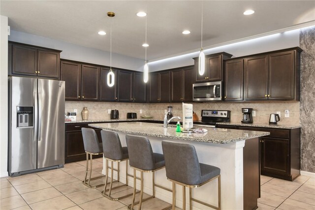 8801 Macapa Dr, Kissimmee, FL 34747 - kitchen with appliances with stainless steel finishes, light tile patterned flooring, dark brown cabinetry, decorative backsplash, and light stone countertops