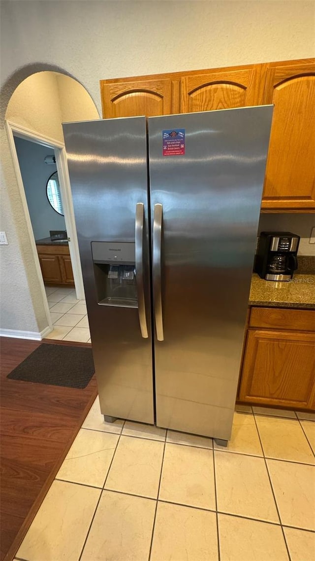 16631 Lazy Breeze Loop, Clermont, FL 34714 - kitchen featuring stainless steel refrigerator with ice dispenser, brown cabinets, light tile patterned floors, dark countertops, and baseboards