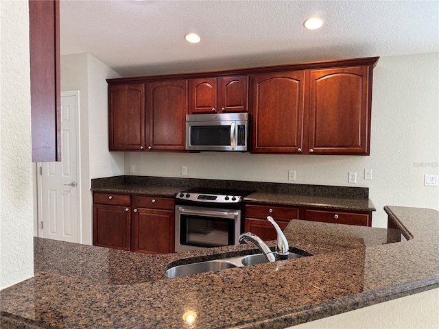 541 Arena Dr, Davenport, FL 33837 - kitchen with appliances with stainless steel finishes, a sink, a textured wall, dark stone counters, and a textured ceiling