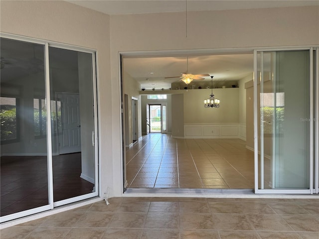 541 Arena Dr, Davenport, FL 33837 - empty room featuring a ceiling fan, tile patterned floors, a decorative wall, a chandelier, and a wainscoted wall