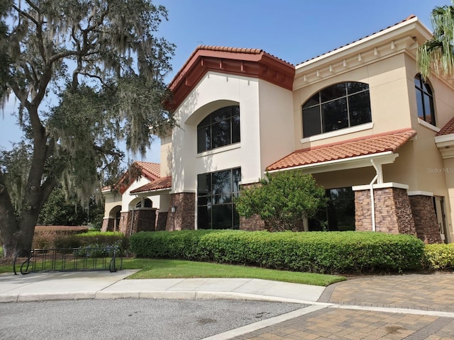 541 Arena Dr, Davenport, FL 33837 - mediterranean / spanish home featuring a tile roof, stucco siding, and stone siding