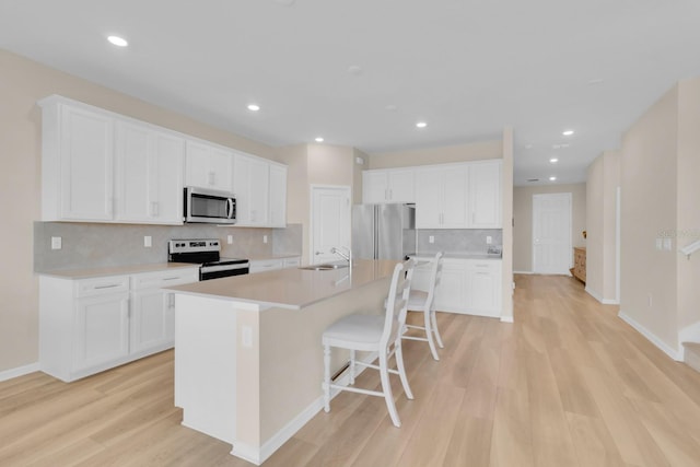 7639 Agrigento St, Clermont, FL 34714 - kitchen featuring stainless steel appliances, light wood-style floors, an island with sink, white cabinets, and recessed lighting