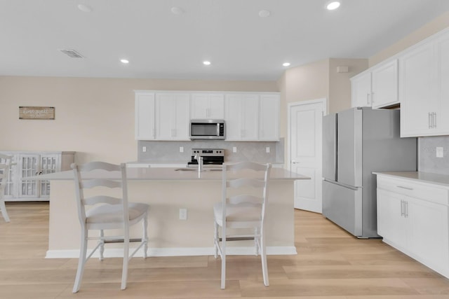 7639 Agrigento St, Clermont, FL 34714 - kitchen featuring stainless steel appliances, light wood-style floors, a kitchen breakfast bar, a center island with sink, and recessed lighting