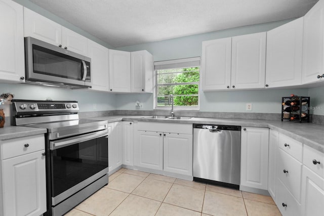 12434 Sullivan Rd, Clermont, FL 34715 - kitchen featuring stainless steel appliances, white cabinets, light tile patterned floors, light countertops, and a textured ceiling