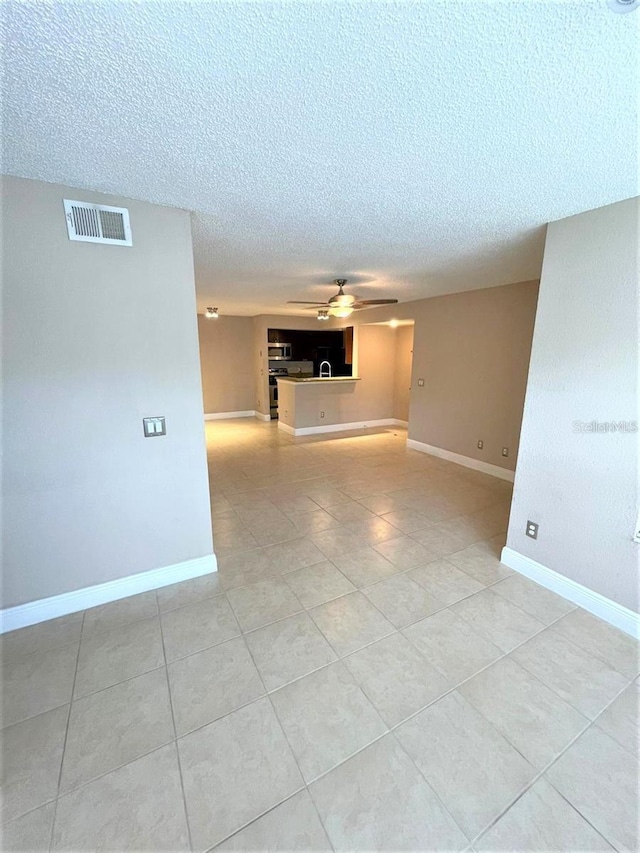 5116 Conroy Rd Unit 411, Orlando, FL 32811 - empty room featuring a textured ceiling, light tile patterned floors, ceiling fan, and baseboards