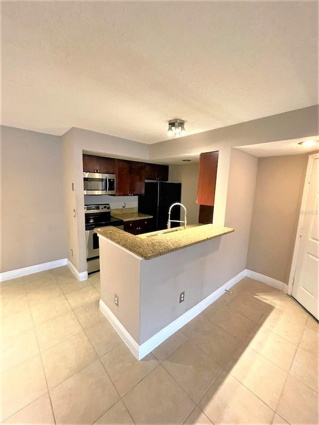 5116 Conroy Rd Unit 411, Orlando, FL 32811 - kitchen featuring appliances with stainless steel finishes, a peninsula, light tile patterned floors, baseboards, and a textured ceiling
