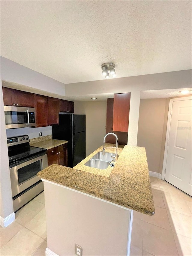 5116 Conroy Rd Unit 411, Orlando, FL 32811 - kitchen featuring stainless steel appliances, a sink, light tile patterned floors, light stone countertops, and baseboards