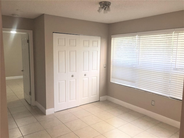 5116 Conroy Rd Unit 411, Orlando, FL 32811 - unfurnished bedroom with light tile patterned flooring, a closet, a textured ceiling, and baseboards