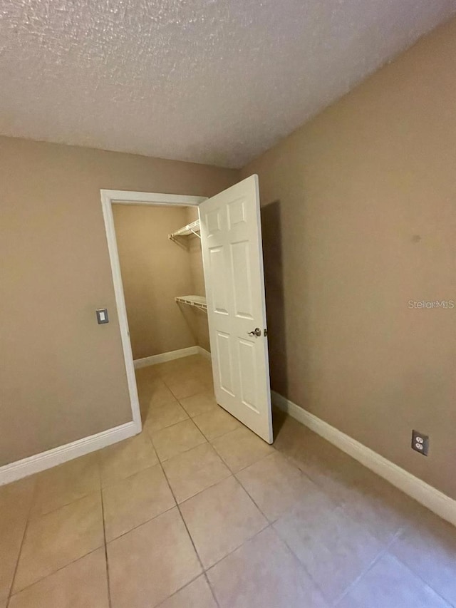 5116 Conroy Rd Unit 411, Orlando, FL 32811 - spare room featuring light tile patterned floors, a textured ceiling, and baseboards