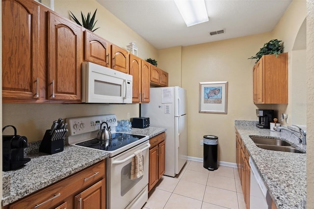 7660 Comrow St Unit 203, Kissimmee, FL 34747 - kitchen featuring white appliances, a sink, light tile patterned floors, and brown cabinetry