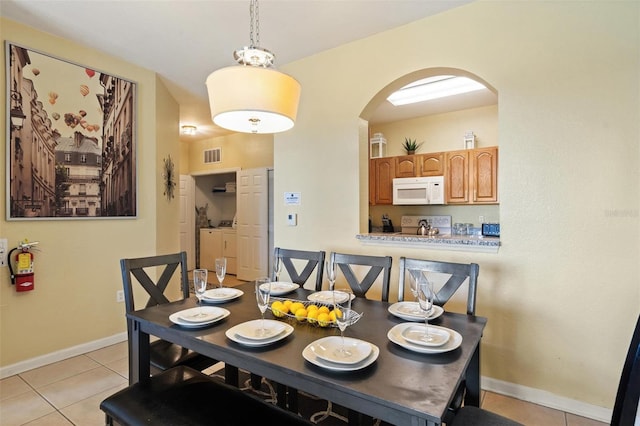 7660 Comrow St Unit 203, Kissimmee, FL 34747 - dining room with arched walkways, washing machine and clothes dryer, light tile patterned floors, and baseboards