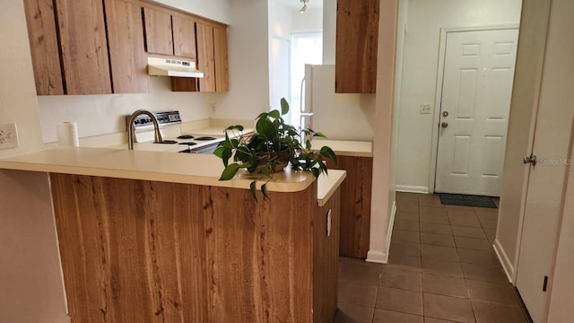6600 121st Ave Unit 5, Largo, FL 33773 - kitchen with under cabinet range hood, stove, dark tile patterned floors, brown cabinets, and light countertops