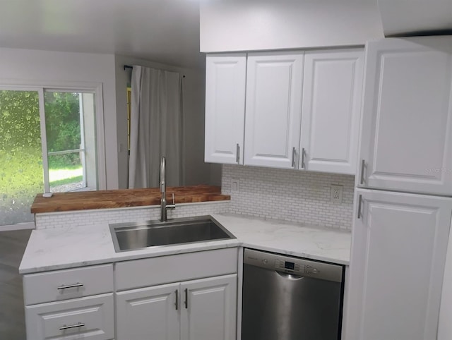 4674 Pembrook Pl Unit J 101, Orlando, FL 32811 - kitchen featuring stainless steel dishwasher, tasteful backsplash, white cabinets, a peninsula, and light stone countertops