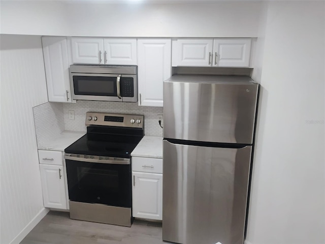 4674 Pembrook Pl Unit J 101, Orlando, FL 32811 - kitchen featuring appliances with stainless steel finishes, light wood-type flooring, white cabinetry, and tasteful backsplash
