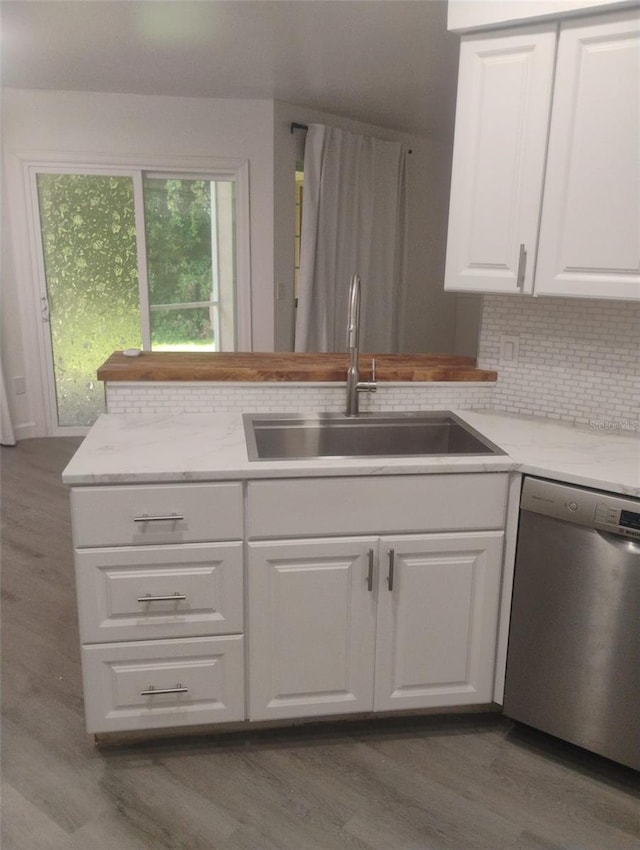 4674 Pembrook Pl Unit J 101, Orlando, FL 32811 - kitchen with dishwasher, wood finished floors, white cabinets, backsplash, and light stone countertops