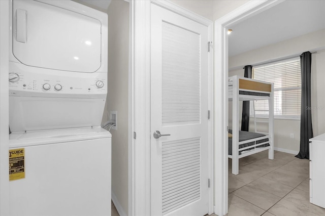 3180 Paradox Cir Unit 304, Kissimmee, FL 34746 - laundry area with stacked washer / drying machine, light tile patterned flooring, and baseboards