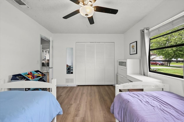 930 Chickadee Dr, Port Orange, FL 32127 - bedroom featuring wood finished floors, a textured ceiling, a closet, and a ceiling fan