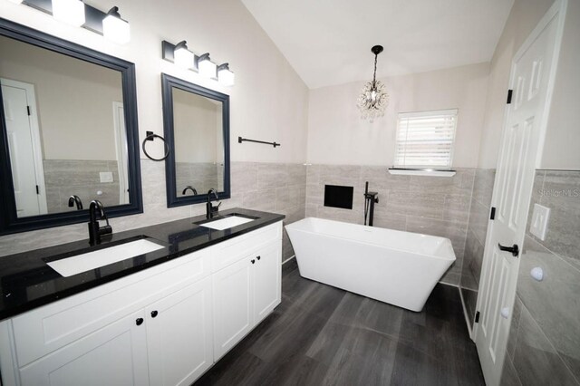 5118 Log Wagon Rd, Ocoee, FL 34761 - bathroom featuring tile walls, a freestanding bath, double vanity, wood finished floors, and a chandelier