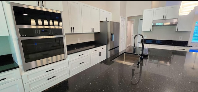 5118 Log Wagon Rd, Ocoee, FL 34761 - kitchen featuring under cabinet range hood, appliances with stainless steel finishes, a sink, white cabinets, and dark stone countertops