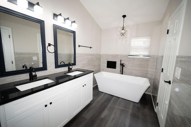 5118 Log Wagon Rd, Ocoee, FL 34761 - bathroom featuring tile walls, a freestanding bath, double vanity, wood finished floors, and a chandelier
