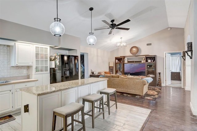10711 Lake Hill Dr, Clermont, FL 34711 - kitchen with black fridge, lofted ceiling, a ceiling fan, a breakfast bar area, and white cabinets