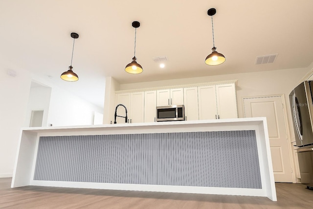 313 Bass Ct, Kissimmee, FL 34759 - kitchen with stainless steel appliances, hanging light fixtures, and white cabinets