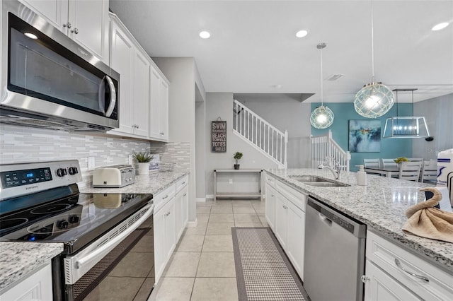 720 Gardenia Ln, Davenport, FL 33897 - kitchen with stainless steel appliances, backsplash, white cabinets, light tile patterned floors, and hanging light fixtures
