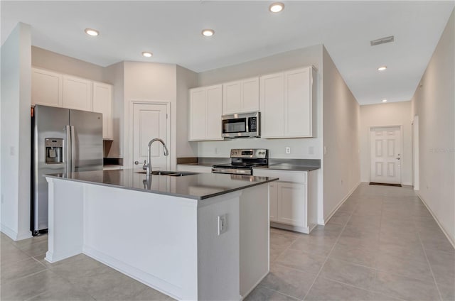 865 Citrus Reserve Blvd, Davenport, FL 33837 - kitchen featuring stainless steel appliances, a sink, dark countertops, an island with sink, and white cabinets