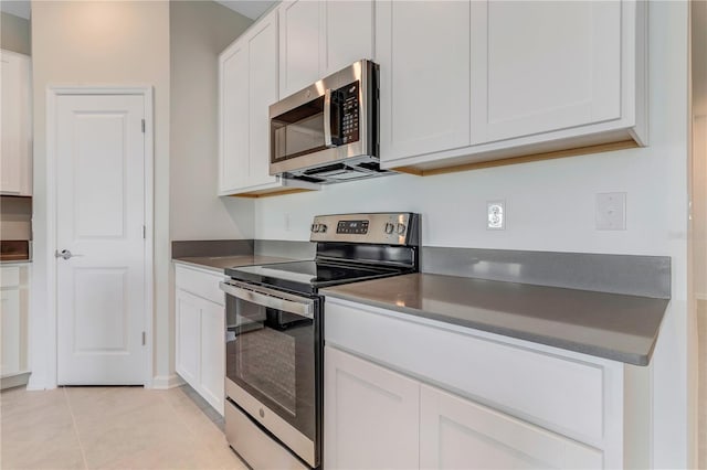 865 Citrus Reserve Blvd, Davenport, FL 33837 - kitchen featuring appliances with stainless steel finishes, light tile patterned flooring, white cabinetry, and dark countertops