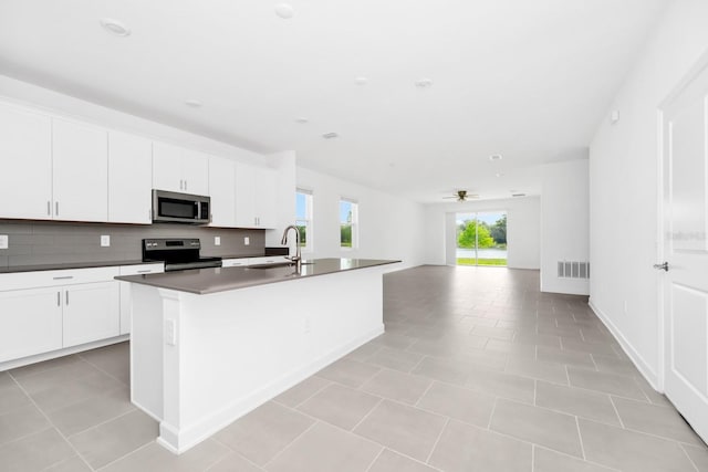 1596 Contentment Loop, Kissimmee, FL 34744 - kitchen featuring stainless steel microwave, range with electric cooktop, open floor plan, a sink, and a kitchen island with sink