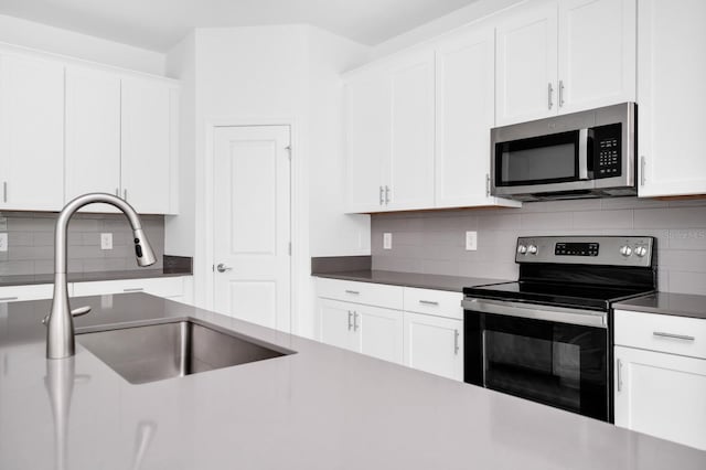1596 Contentment Loop, Kissimmee, FL 34744 - kitchen featuring stainless steel appliances, a sink, backsplash, and white cabinets