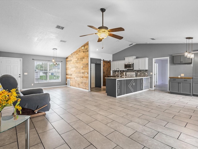 112 Lake Butler Ave, Haines City, FL 33844 - living room with vaulted ceiling, a ceiling fan, a barn door, a chandelier, and light tile patterned floors