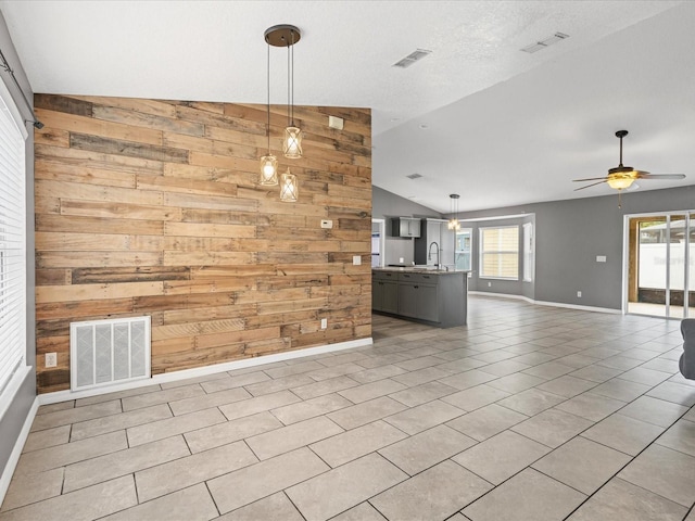 112 Lake Butler Ave, Haines City, FL 33844 - unfurnished living room featuring lofted ceiling, a sink, wood walls, plenty of natural light, and baseboards