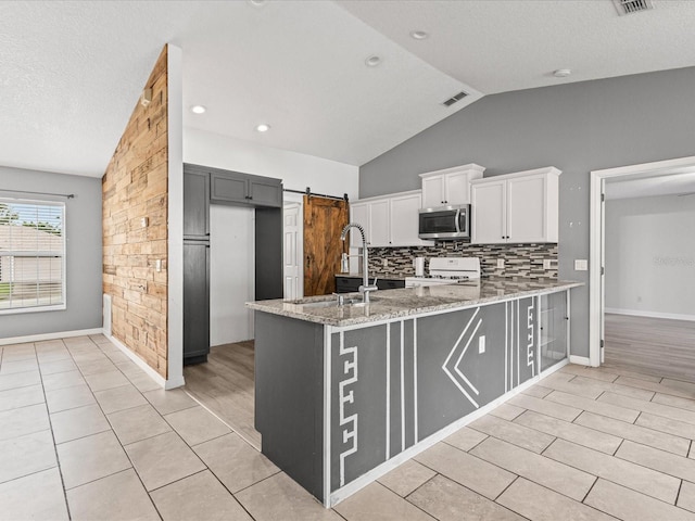 112 Lake Butler Ave, Haines City, FL 33844 - kitchen with stainless steel microwave, white range, a sink, vaulted ceiling, and light stone counters