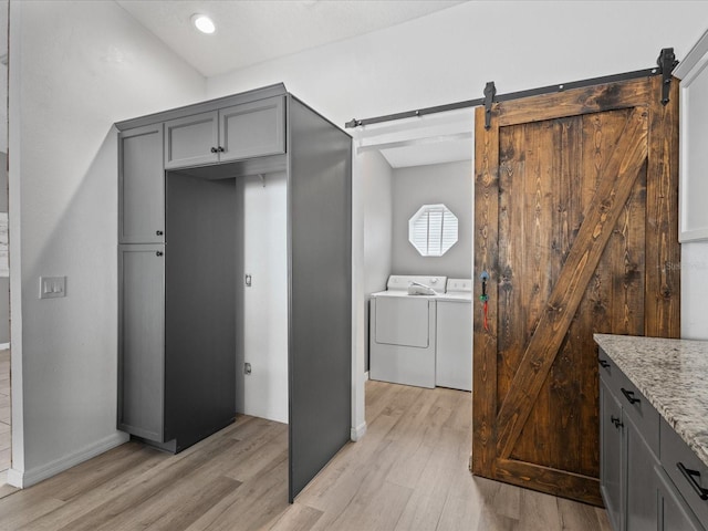 112 Lake Butler Ave, Haines City, FL 33844 - laundry room featuring washing machine and clothes dryer, a barn door, light wood-style floors, and baseboards