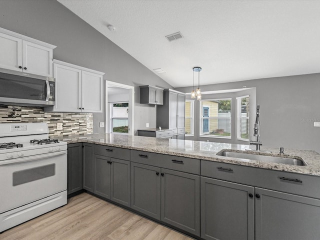 112 Lake Butler Ave, Haines City, FL 33844 - kitchen featuring stainless steel microwave, white range with gas stovetop, gray cabinetry, a sink, and vaulted ceiling