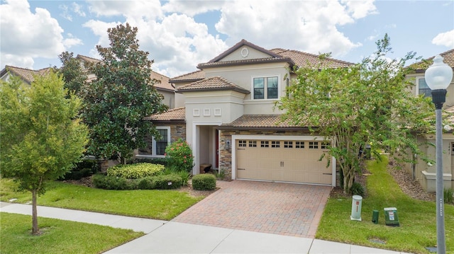 1439 Moon Valley Dr, Davenport, FL 33896 - mediterranean / spanish-style house featuring decorative driveway, a tile roof, stucco siding, an attached garage, and stone siding