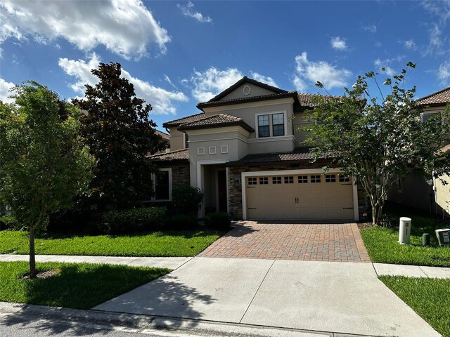 1439 Moon Valley Dr, Davenport, FL 33896 - mediterranean / spanish-style home featuring stone siding, decorative driveway, a tiled roof, and a garage