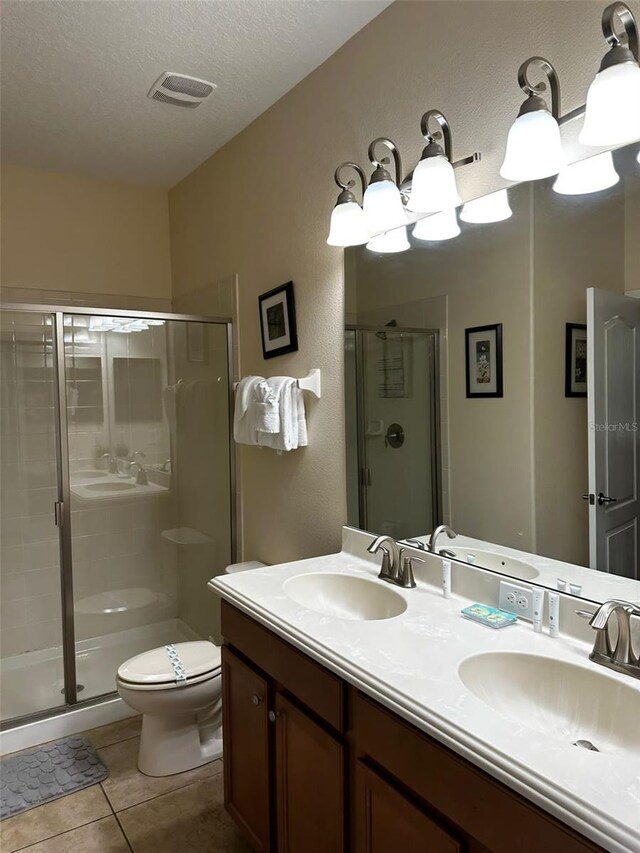 1439 Moon Valley Dr, Davenport, FL 33896 - bathroom featuring a shower stall, double vanity, toilet, tile patterned flooring, and a textured ceiling