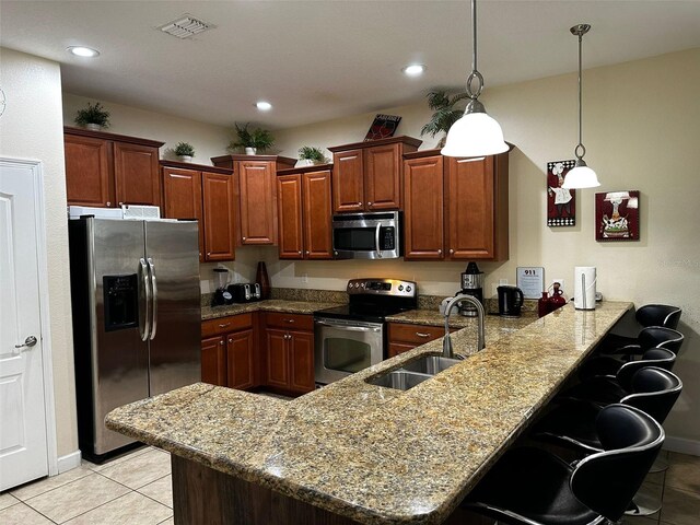 1439 Moon Valley Dr, Davenport, FL 33896 - kitchen with appliances with stainless steel finishes, a sink, a peninsula, light tile patterned flooring, and a breakfast bar