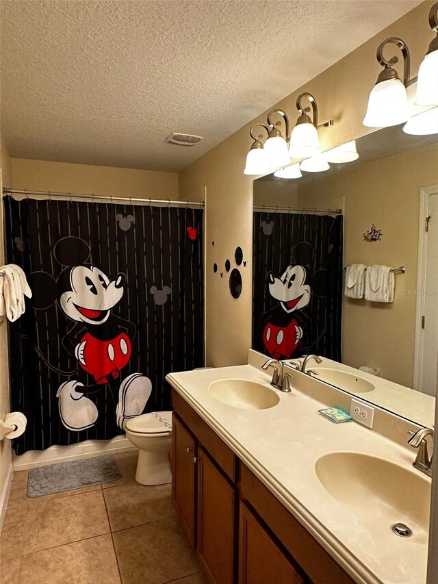 1439 Moon Valley Dr, Davenport, FL 33896 - bathroom with tile patterned flooring, double vanity, toilet, a textured ceiling, and a shower with curtain