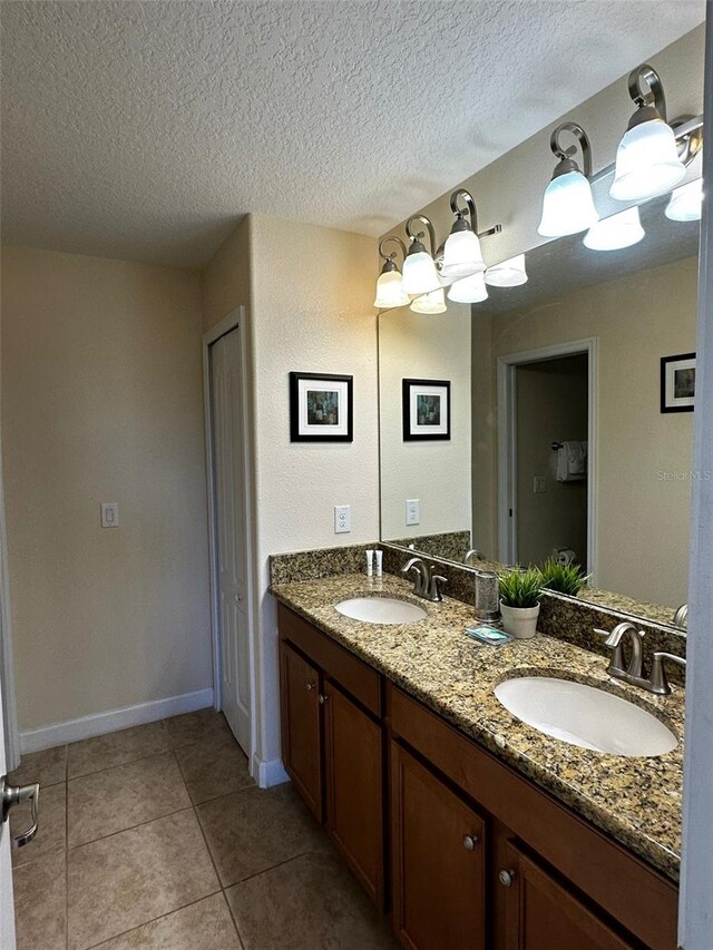 1439 Moon Valley Dr, Davenport, FL 33896 - bathroom with double vanity, a textured ceiling, tile patterned floors, and baseboards