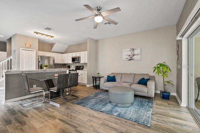 17516 Blessing Dr, Clermont, FL 34714 - living room with ceiling fan, vaulted ceiling, light wood-style floors, and baseboards
