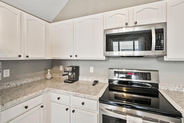 17516 Blessing Dr, Clermont, FL 34714 - kitchen with stainless steel appliances, white cabinetry, lofted ceiling, and light stone counters