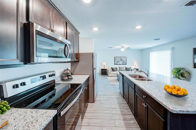 1303 Congo Ct, Kissimmee, FL 34759 - kitchen featuring stainless steel appliances, open floor plan, dark brown cabinetry, light stone countertops, and recessed lighting