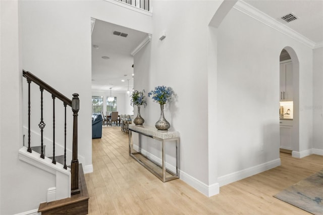 9844 Beach Port Dr, Winter Garden, FL 34787 - foyer entrance with arched walkways, light wood-style floors, crown molding, baseboards, and stairway