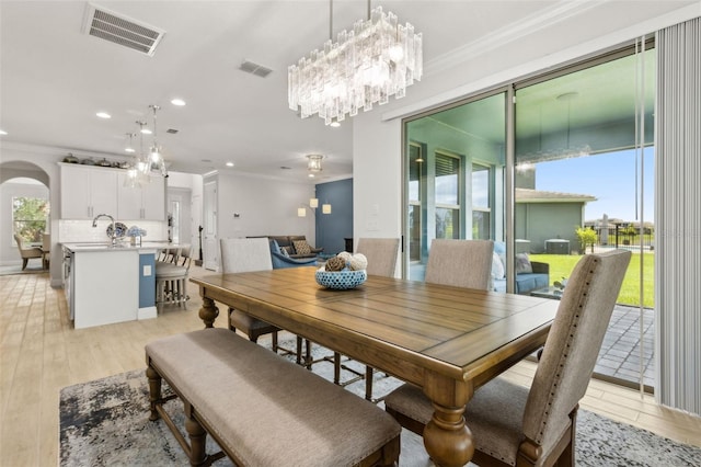 9844 Beach Port Dr, Winter Garden, FL 34787 - dining room featuring ornamental molding, a chandelier, arched walkways, recessed lighting, and light wood-type flooring