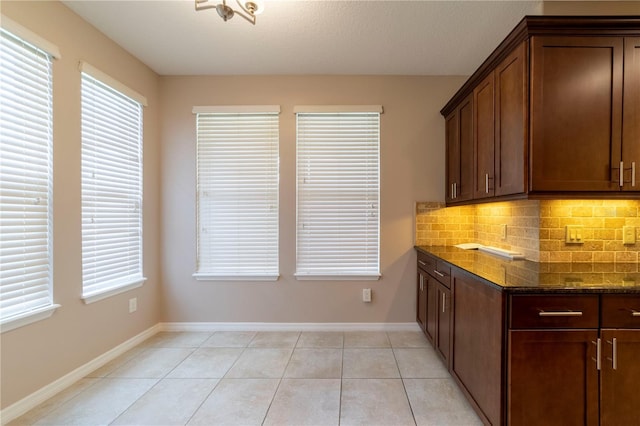 3651 NW 56th Ave, Ocala, FL 34482 - kitchen featuring dark stone countertops, backsplash, light tile patterned floors, and baseboards