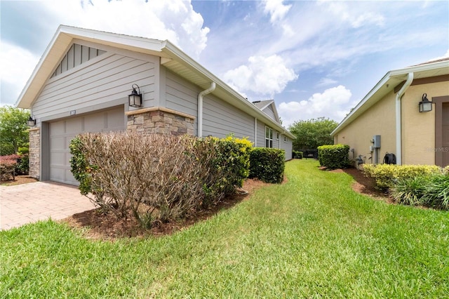 3651 NW 56th Ave, Ocala, FL 34482 - view of side of property featuring stone siding, a lawn, an attached garage, and decorative driveway